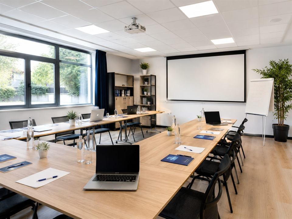 Salle de formation préparée avec tables en U, ordinateurs et écran de projection